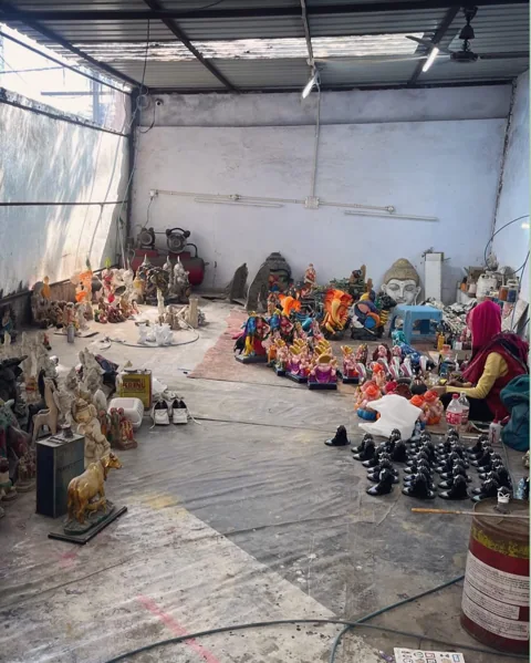 Artisan at work among colourful Ganesha sculptures in a workshop